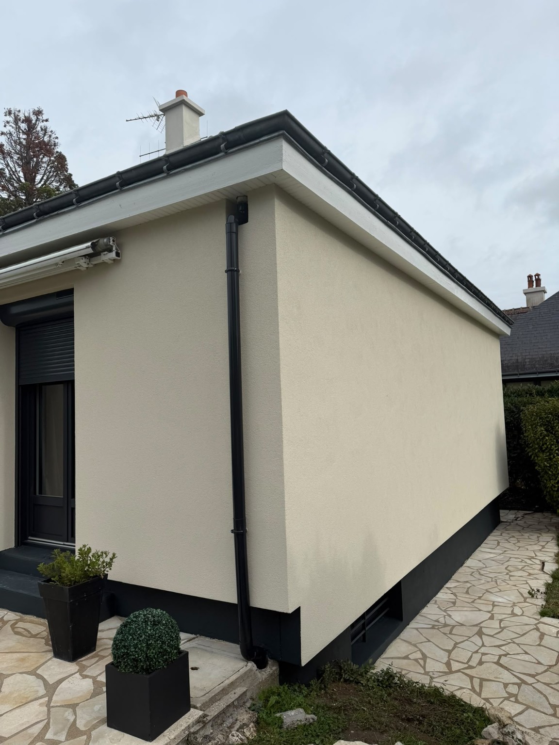 Angle de maison avec ravalement clair et descente d'eau anthracite